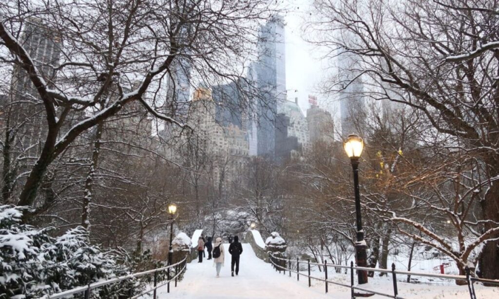 NEW YORK, NY - JANUARY 16: People walk over the Gapstow Bridge as snow falls in Central Park on January 16, 2024 in New York City. The City received a rare accumulation of snow overnight. (Photo by Gary Hershorn/Getty Images)