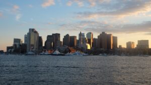Boston skyline glowing at sunset over the harbor.