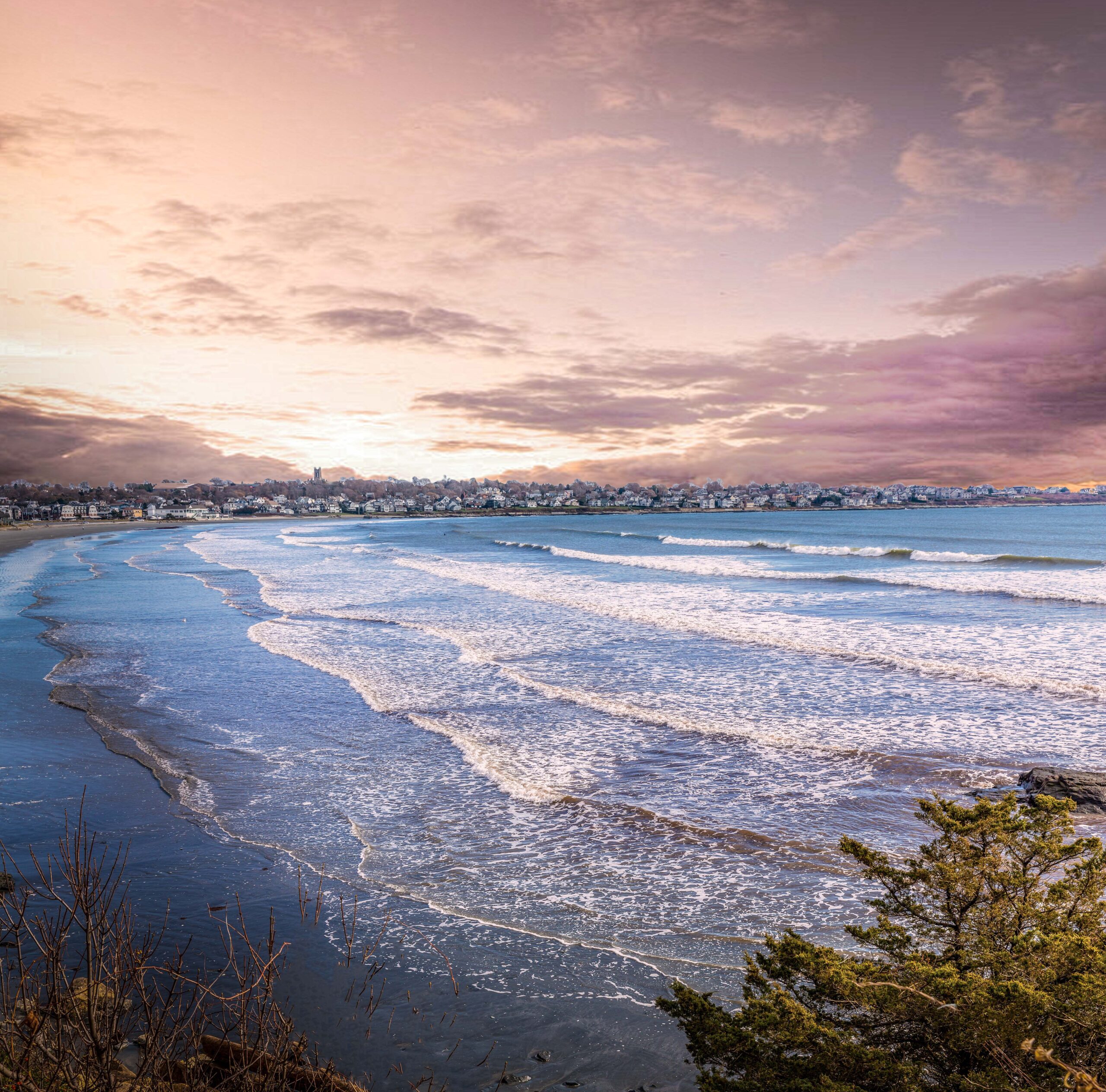 Ocean waves rolling toward a coastal town at sunset