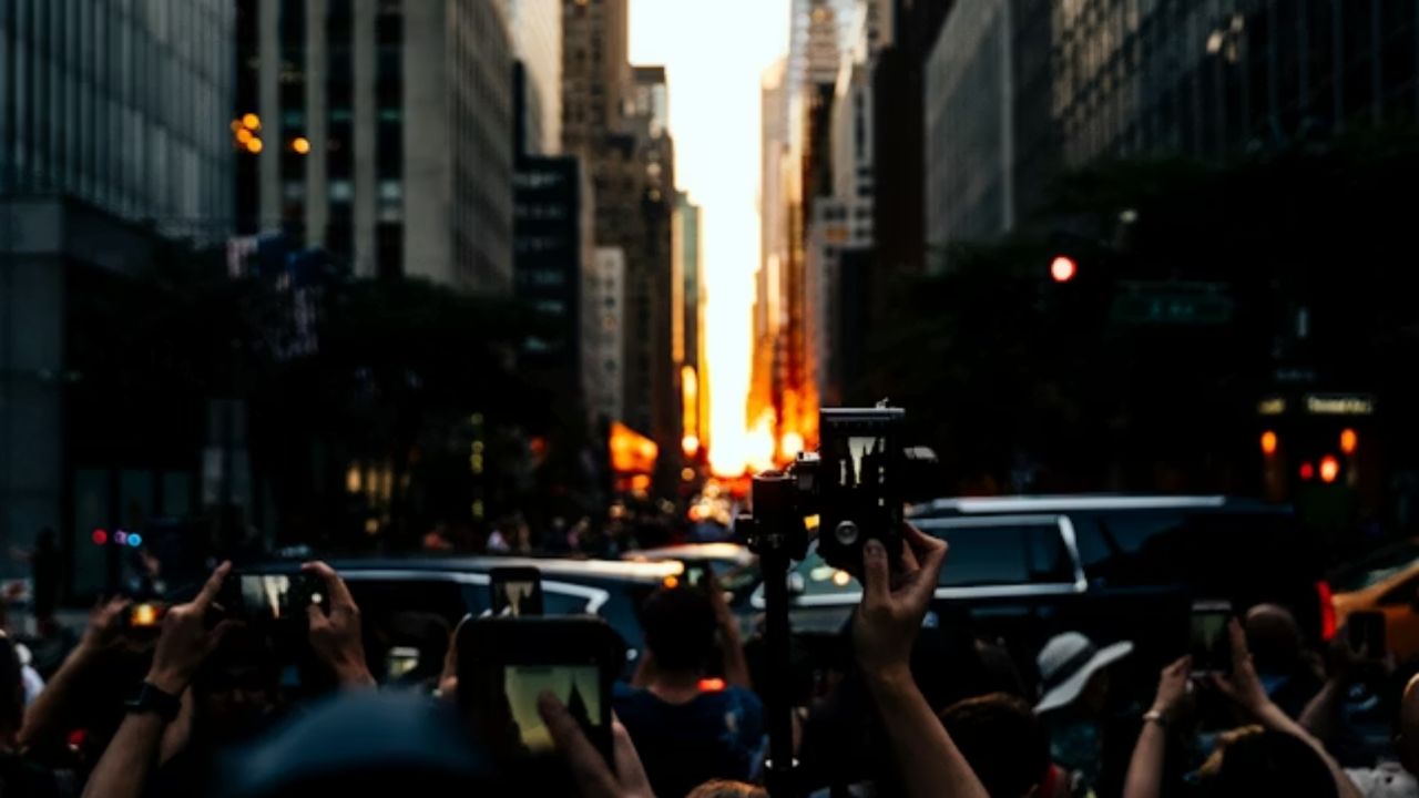  Crowds photographing Manhattanhenge sunset aligned with NYC street grid and Chrysler Building in background.