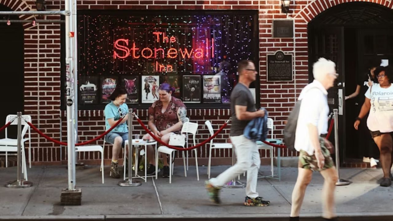 Stonewall Inn exterior with rainbow flags and sidewalk activity.