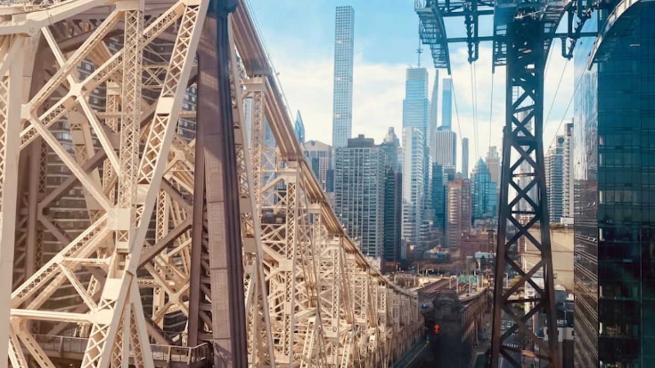 Roosevelt Island Tramway cables beside Queensboro Bridge skyline.