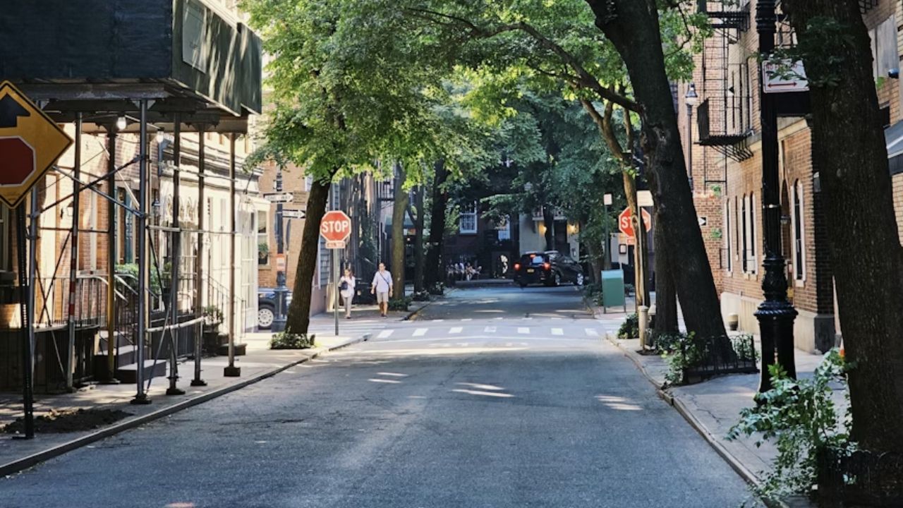 Tree-lined Greenwich Village street with brick buildings.