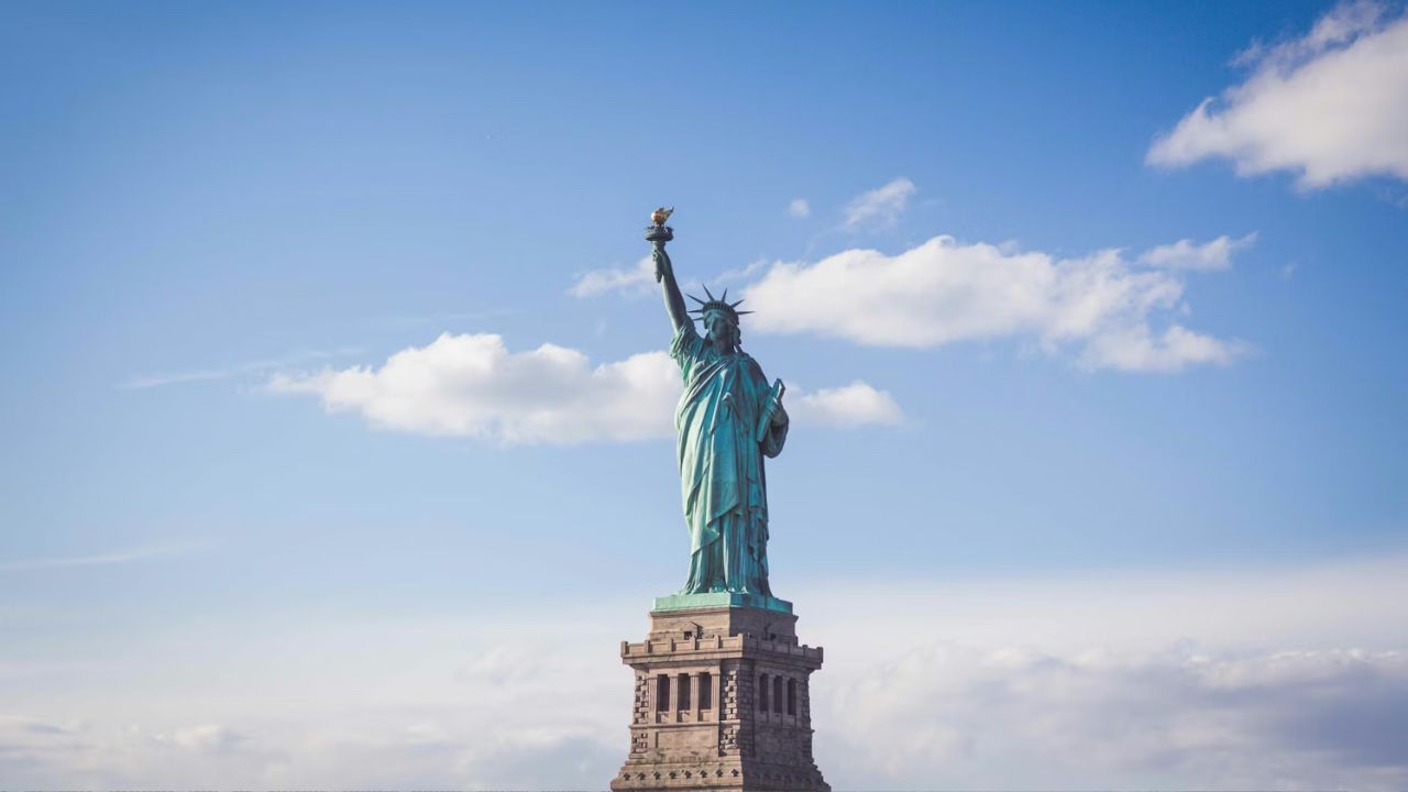 Statue of Liberty standing tall against blue sky clouds.