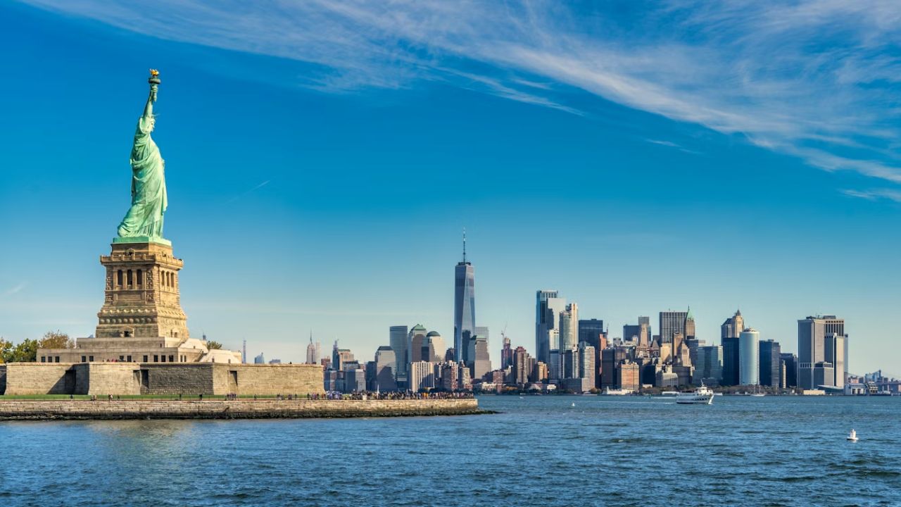 Statue of Liberty with Manhattan skyline across New York Harbor.

