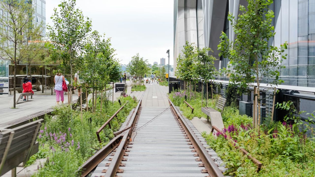  NYC High Line park with tracks, greenery, and people.
