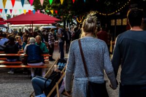 Crowds enjoying food under flags and string lights.