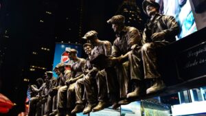 Bronze worker sculptures lit up at Times Square night.