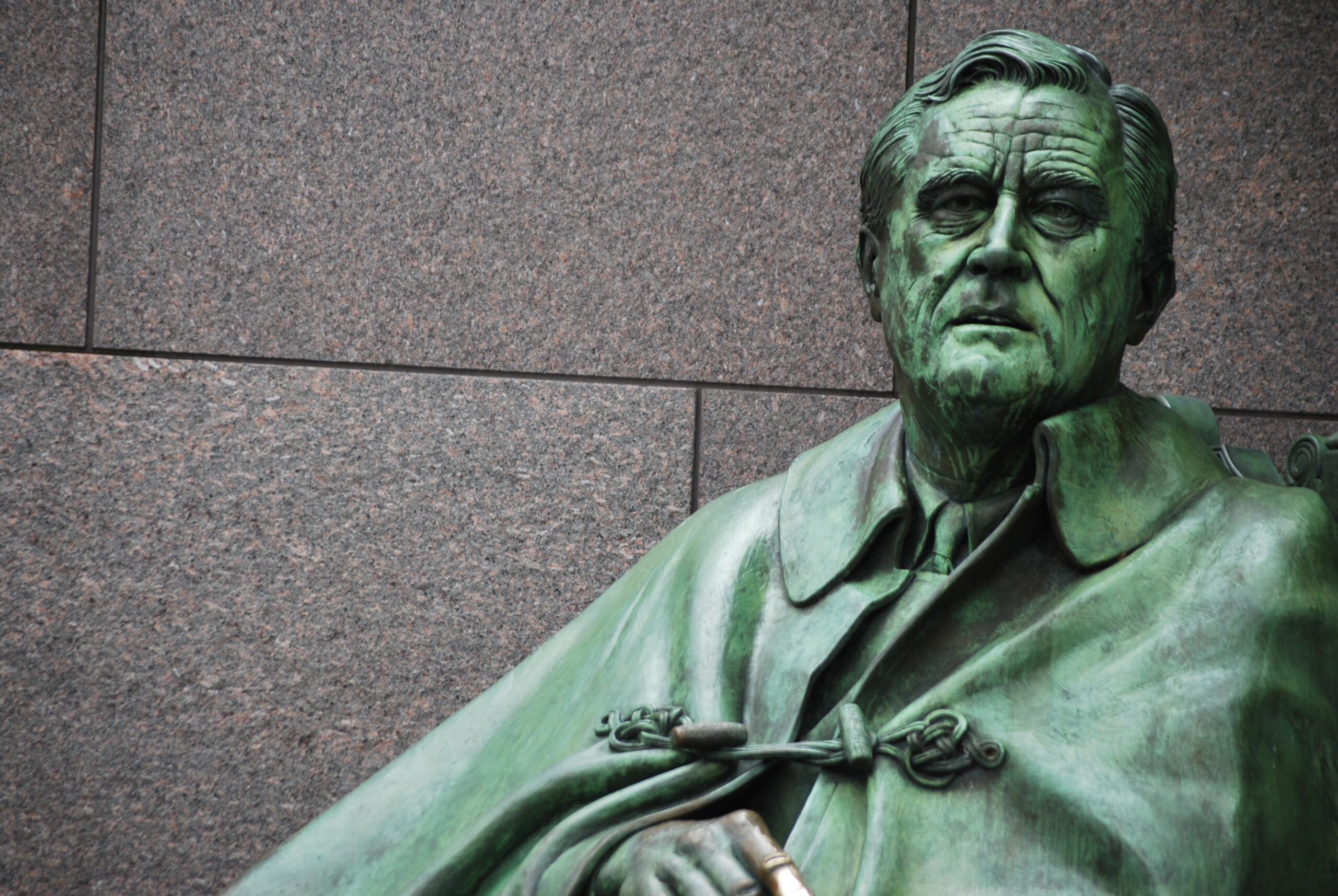 Bronze FDR statue against granite wall, close-up