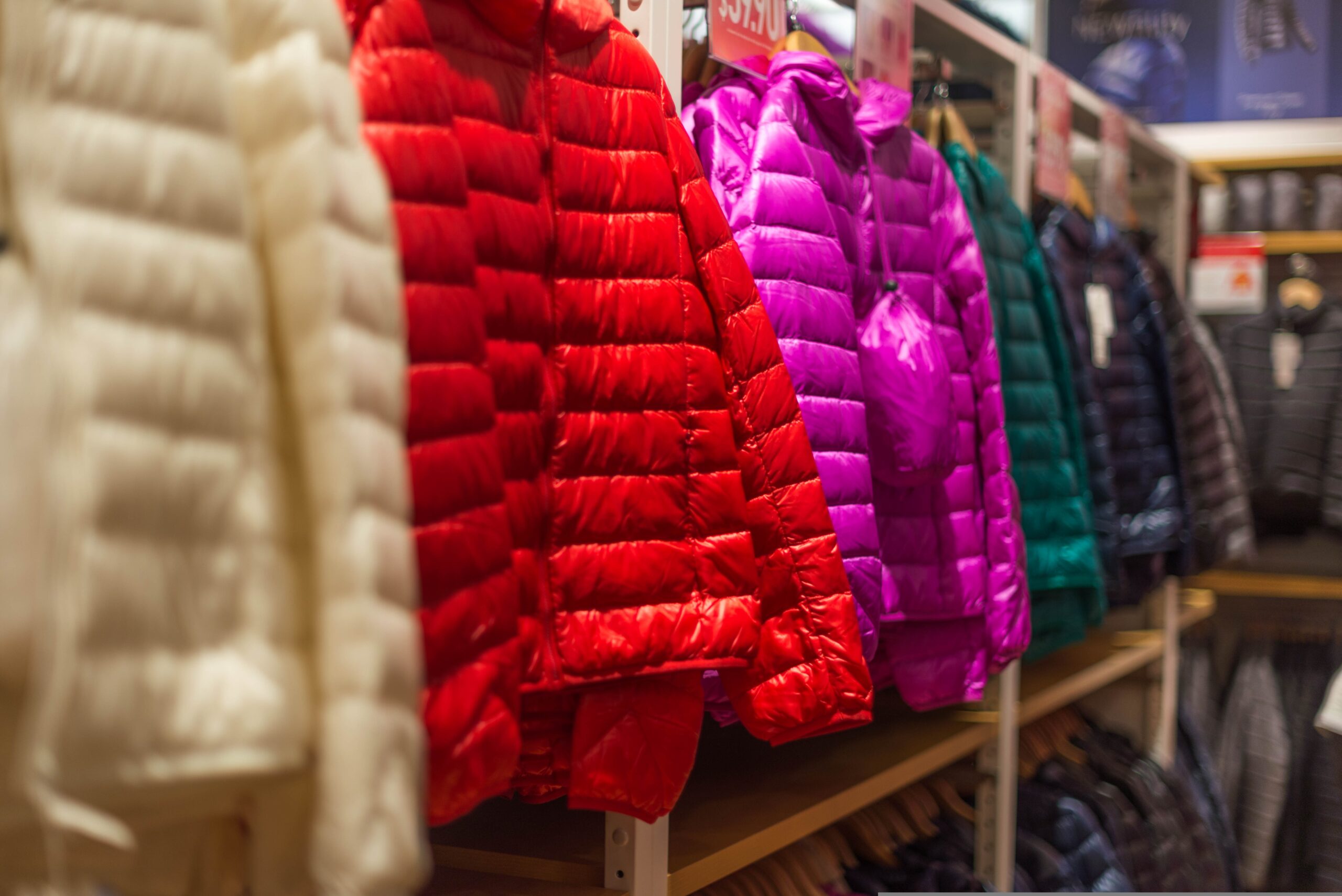 Colorful puffer jackets hanging on retail store rack