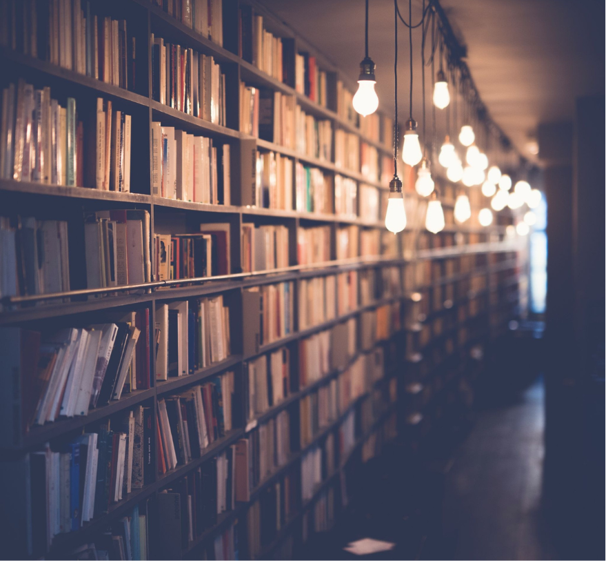 Library bookshelves lit by hanging exposed light bulbs.