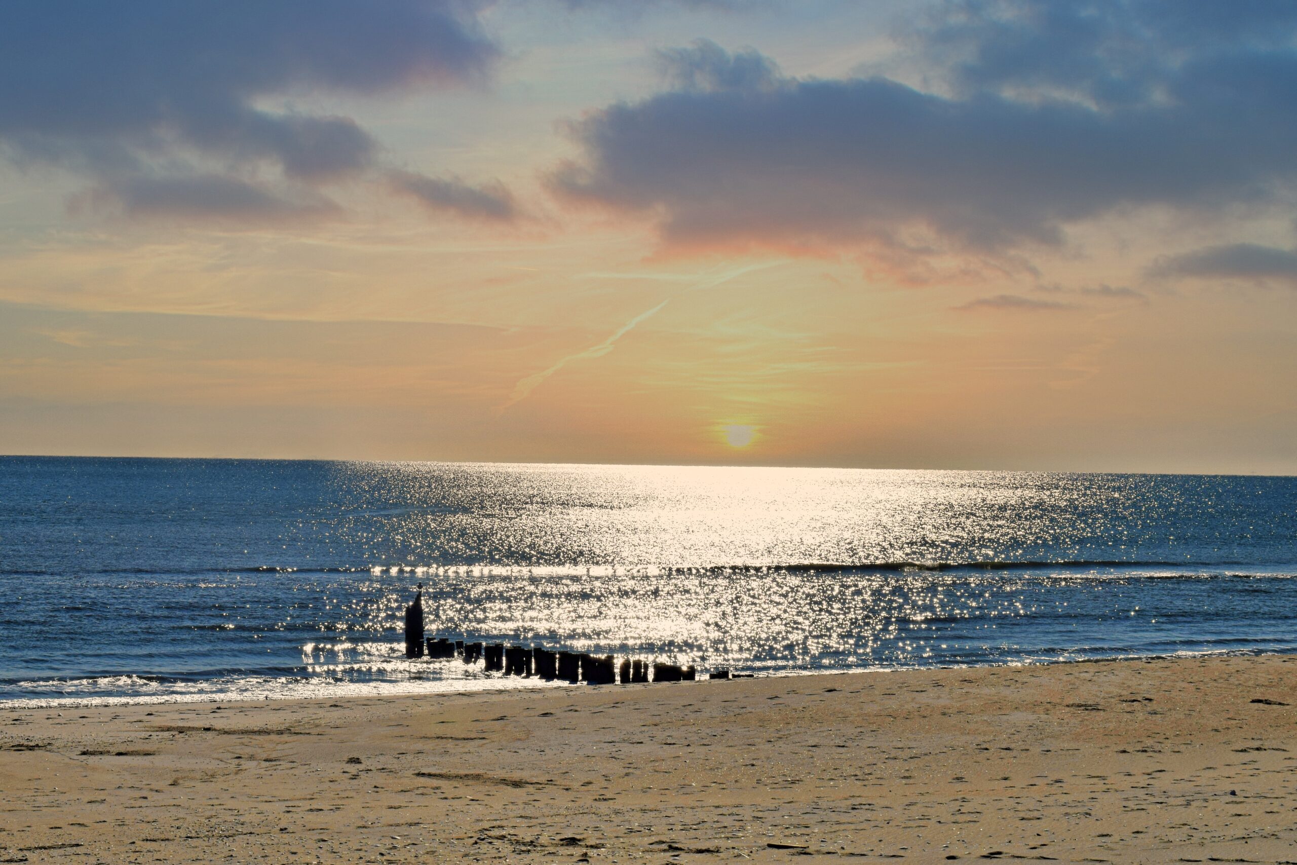 Sunset glinting on ocean waves near a sandy beach