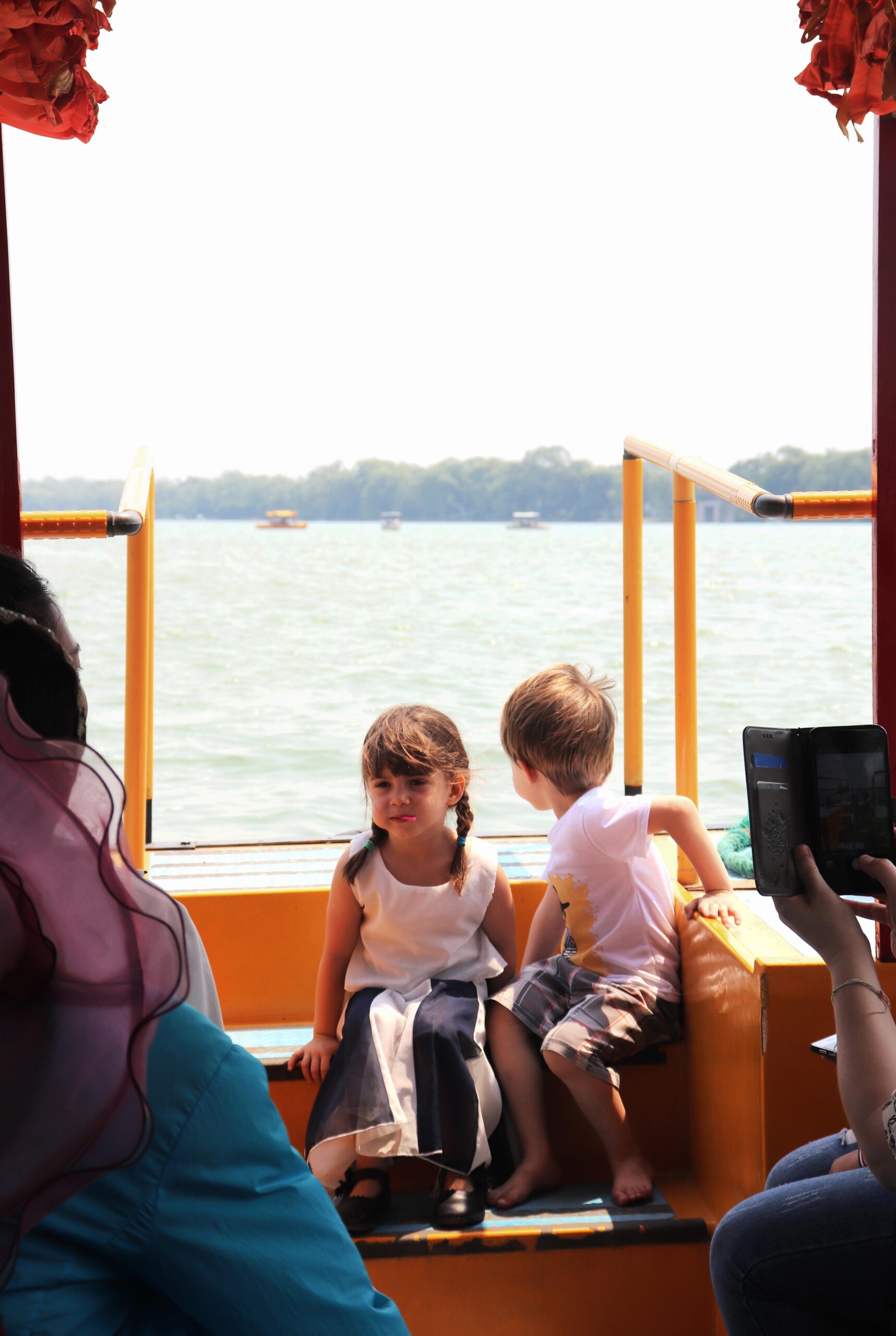Two young children sitting on boat watching lake