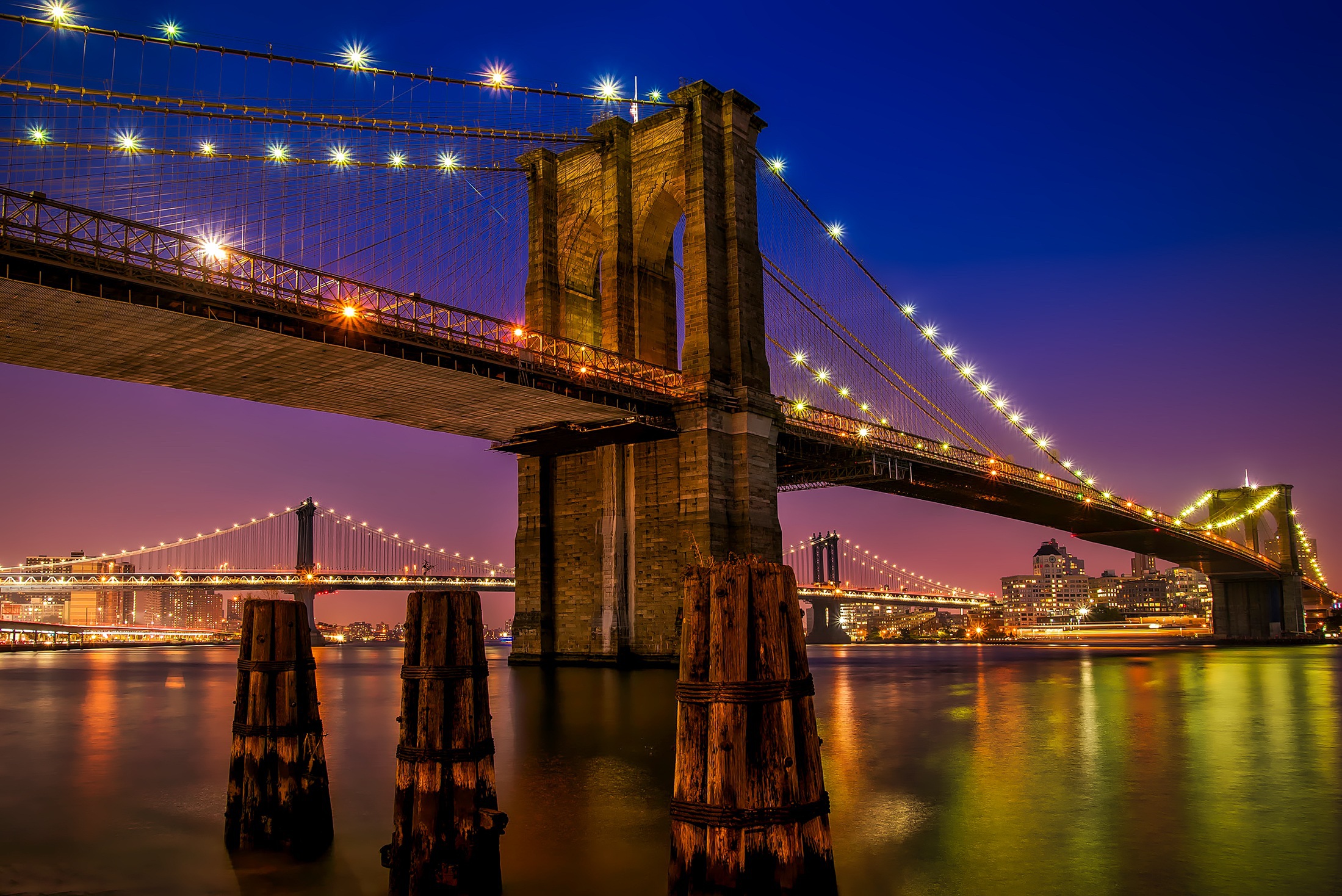 Brooklyn Bridge lit up over the East River at dusk