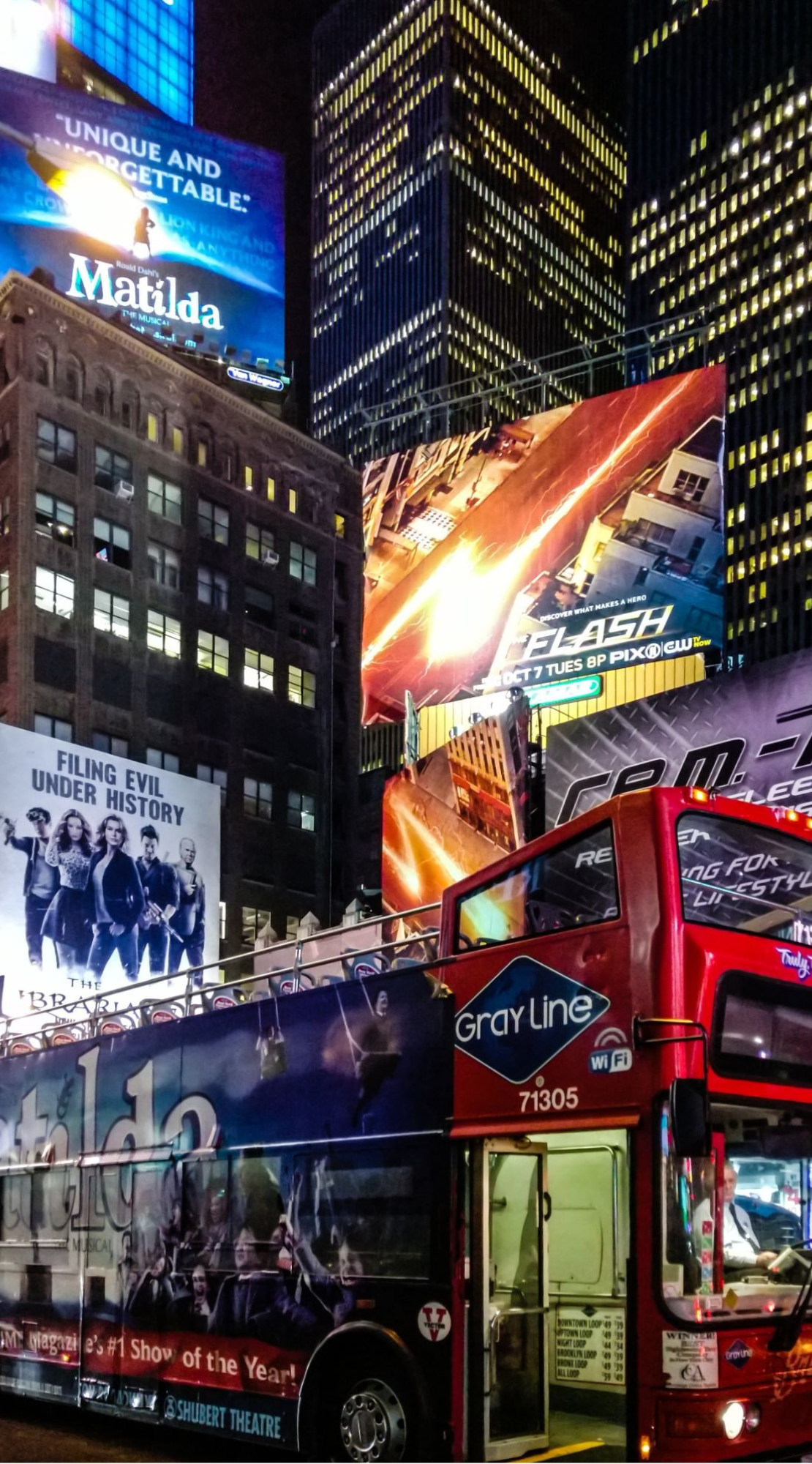 Times Square billboards at night with tour bus.