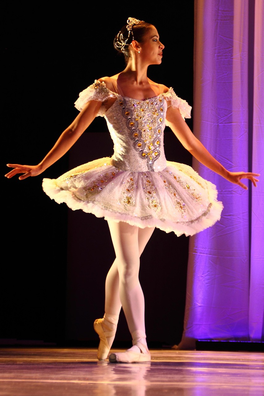 Ballerina in white tutu posing on stage.