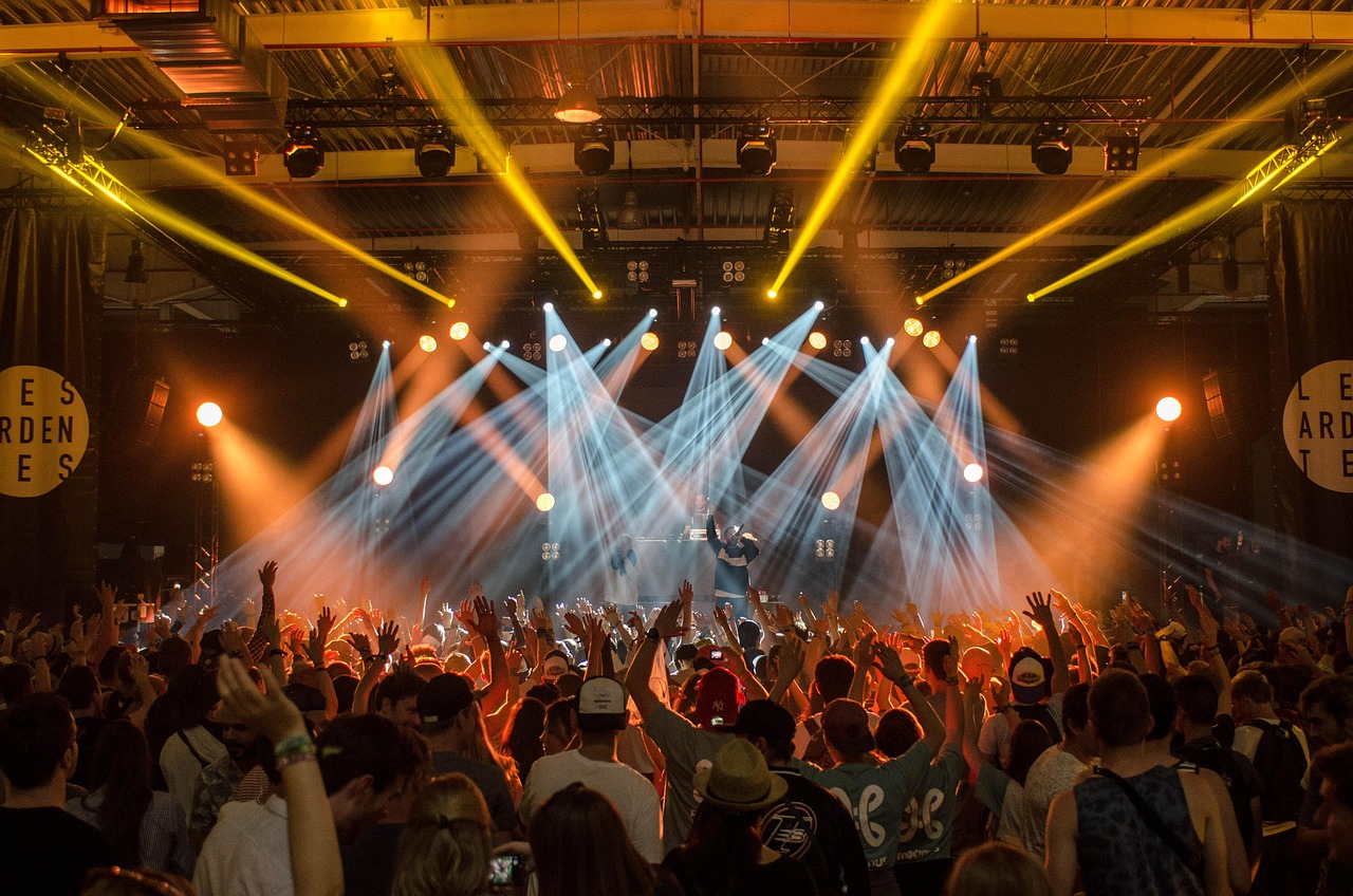 Concert crowd raising hands under colorful stage lights