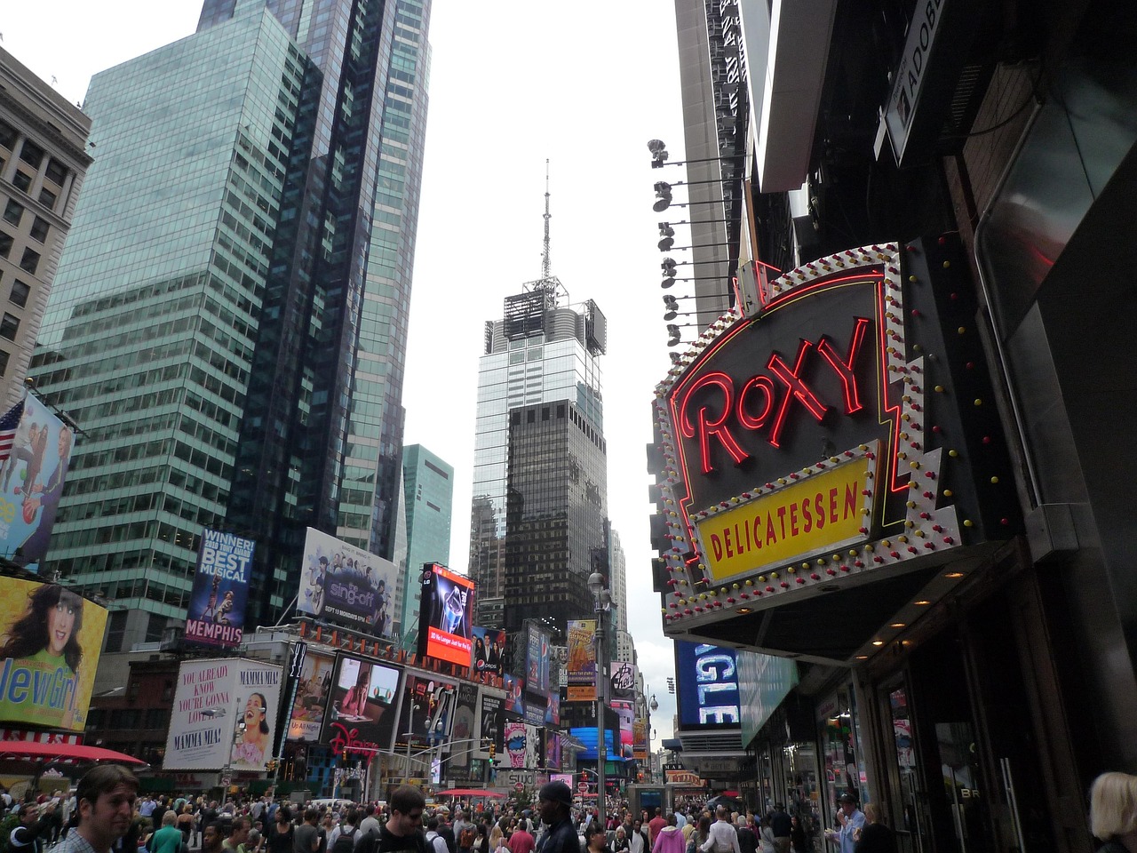 Crowds fill Times Square below the Roxy Delicatessen sign
