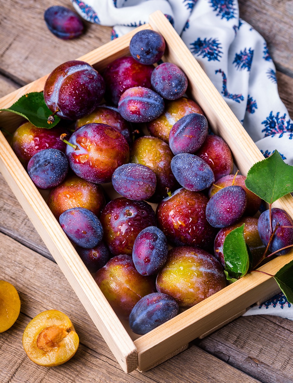 Fresh plums piled in a wooden crate.
