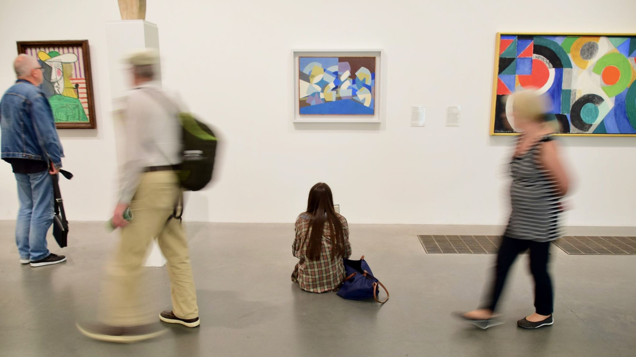 Museum visitors viewing modern art paintings on gallery walls