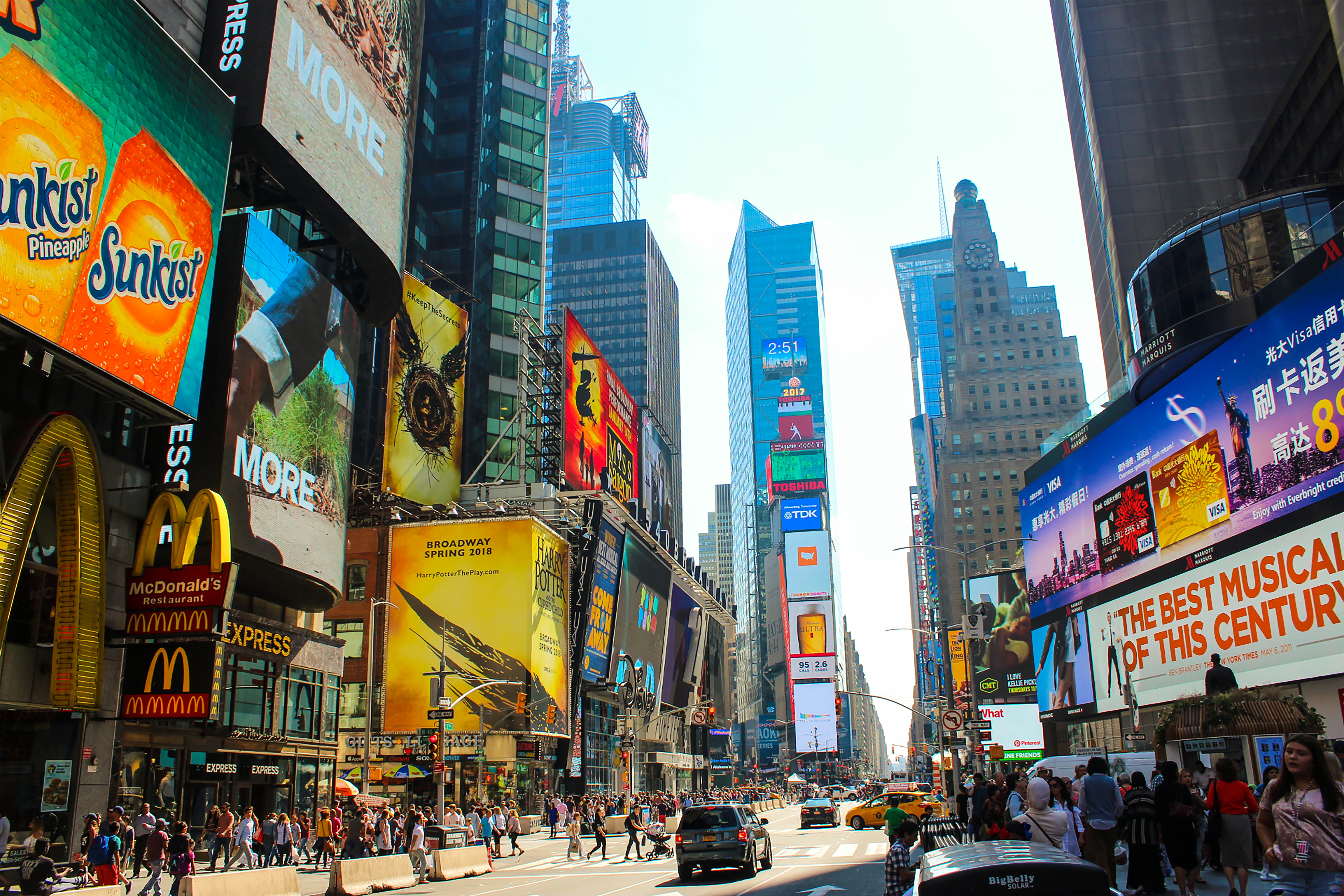 Sunny Times Square street lined with billboards and pedestrians