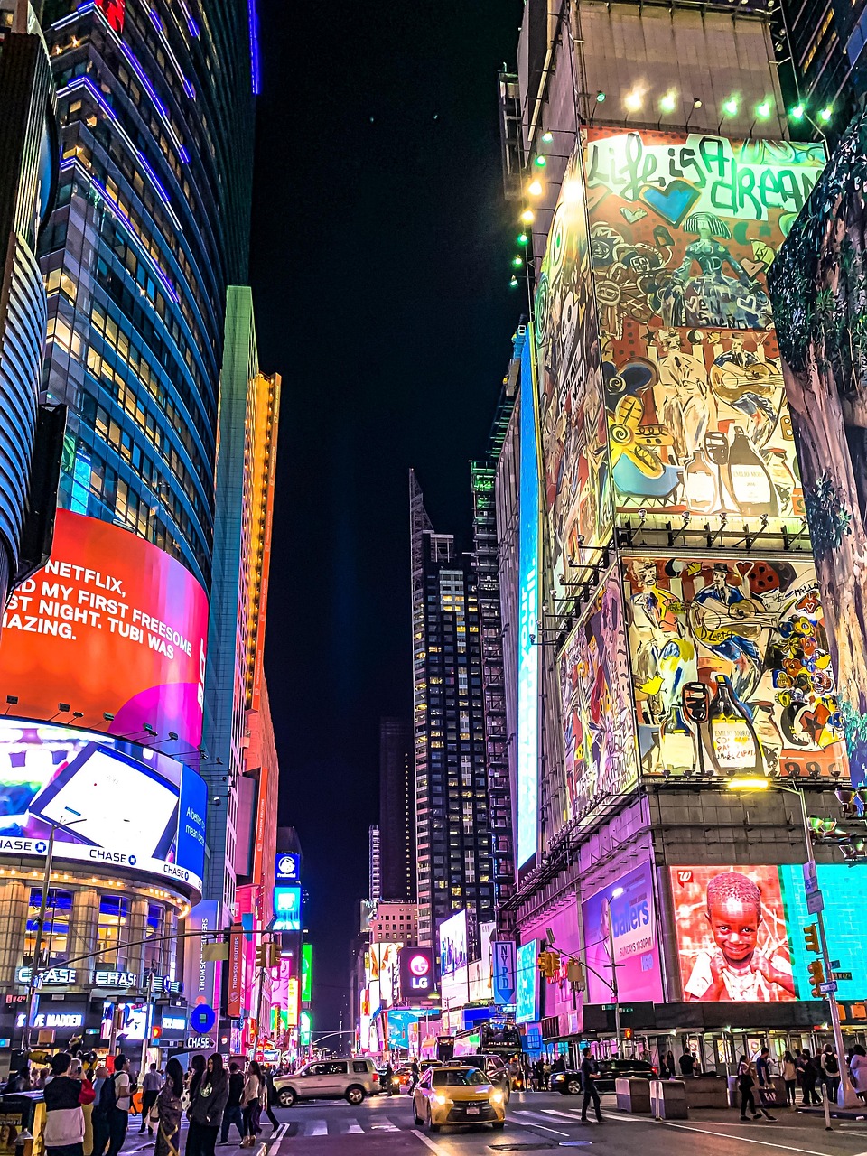 Times Square at night with colorful billboards and yellow taxi