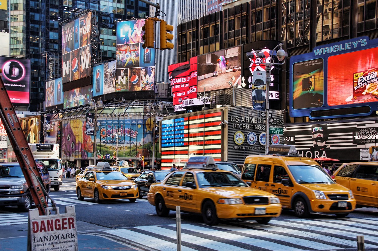 Yellow taxis pass the illuminated flag at Times Square recruiting station